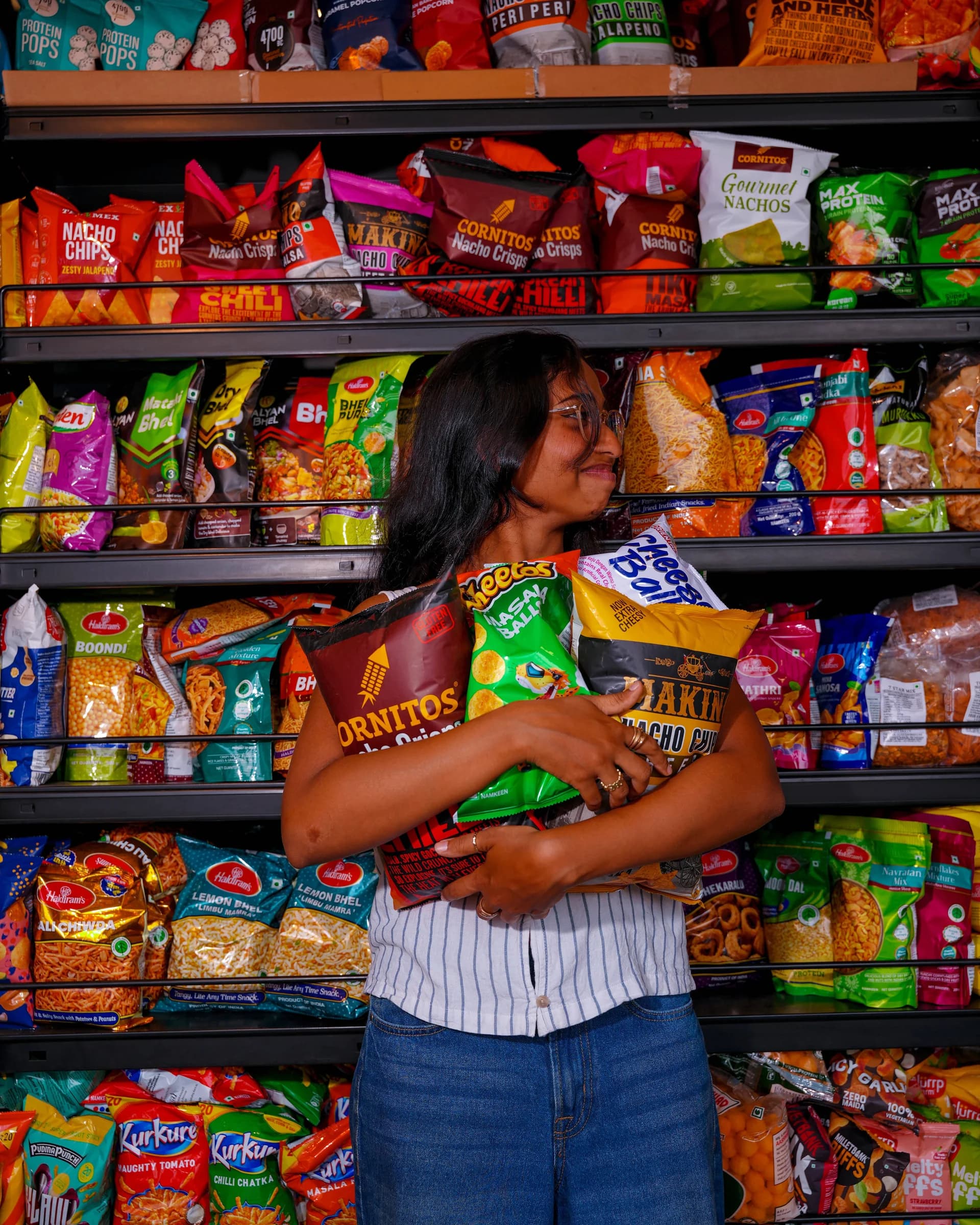 A shopper hugging an armful of snacks in the snack aisle